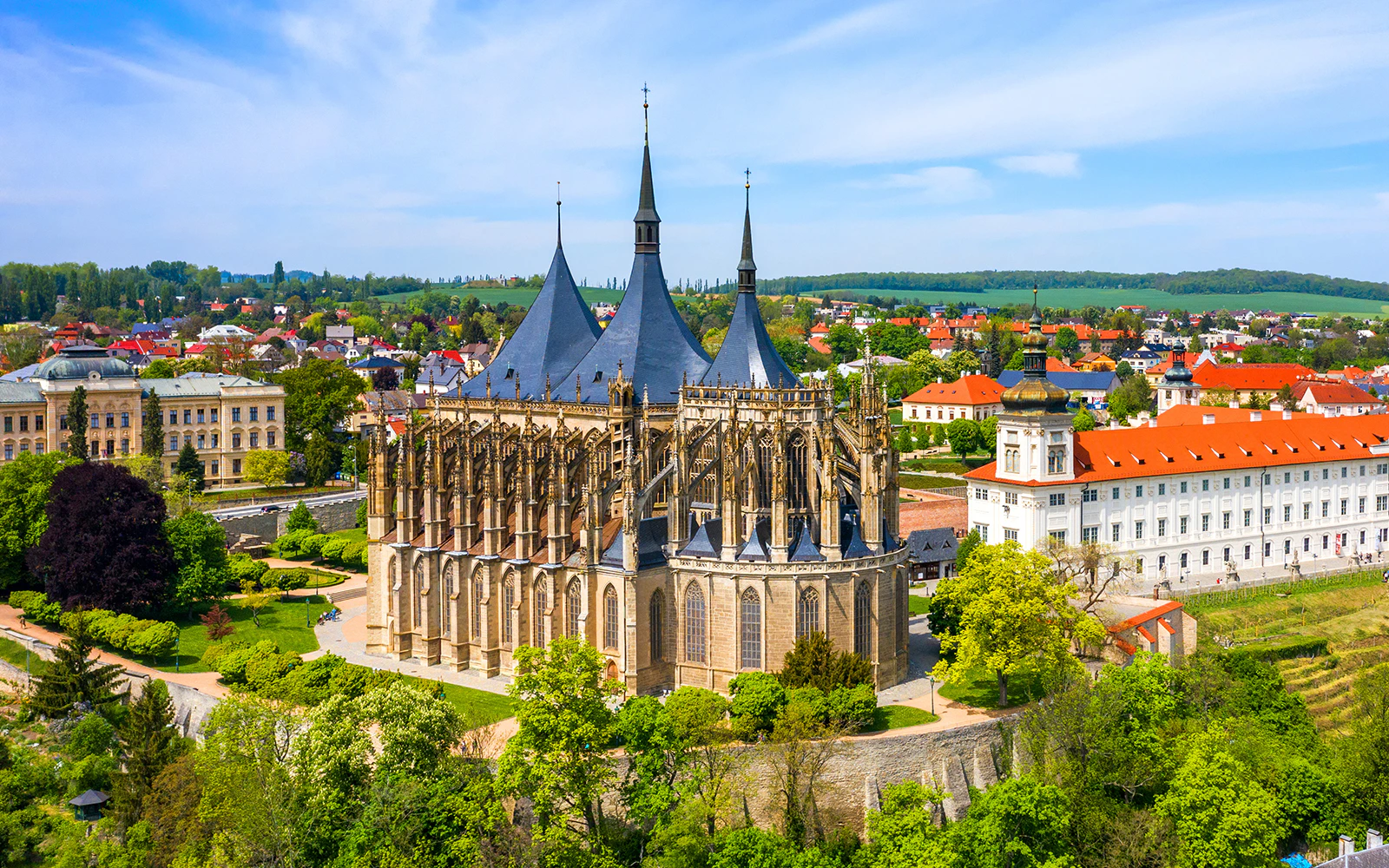 St. Barbara's Church in Kutná Hora, Czech Republic, surrounded by lush greenery and historic buildings.