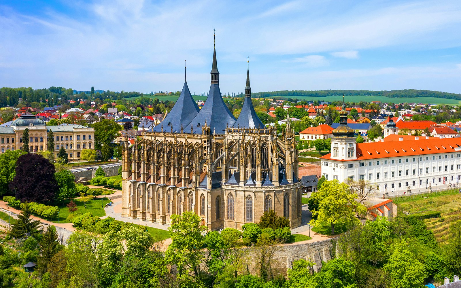 St. Barbara's Church in Kutná Hora, Czech Republic, surrounded by lush greenery and historic buildings.