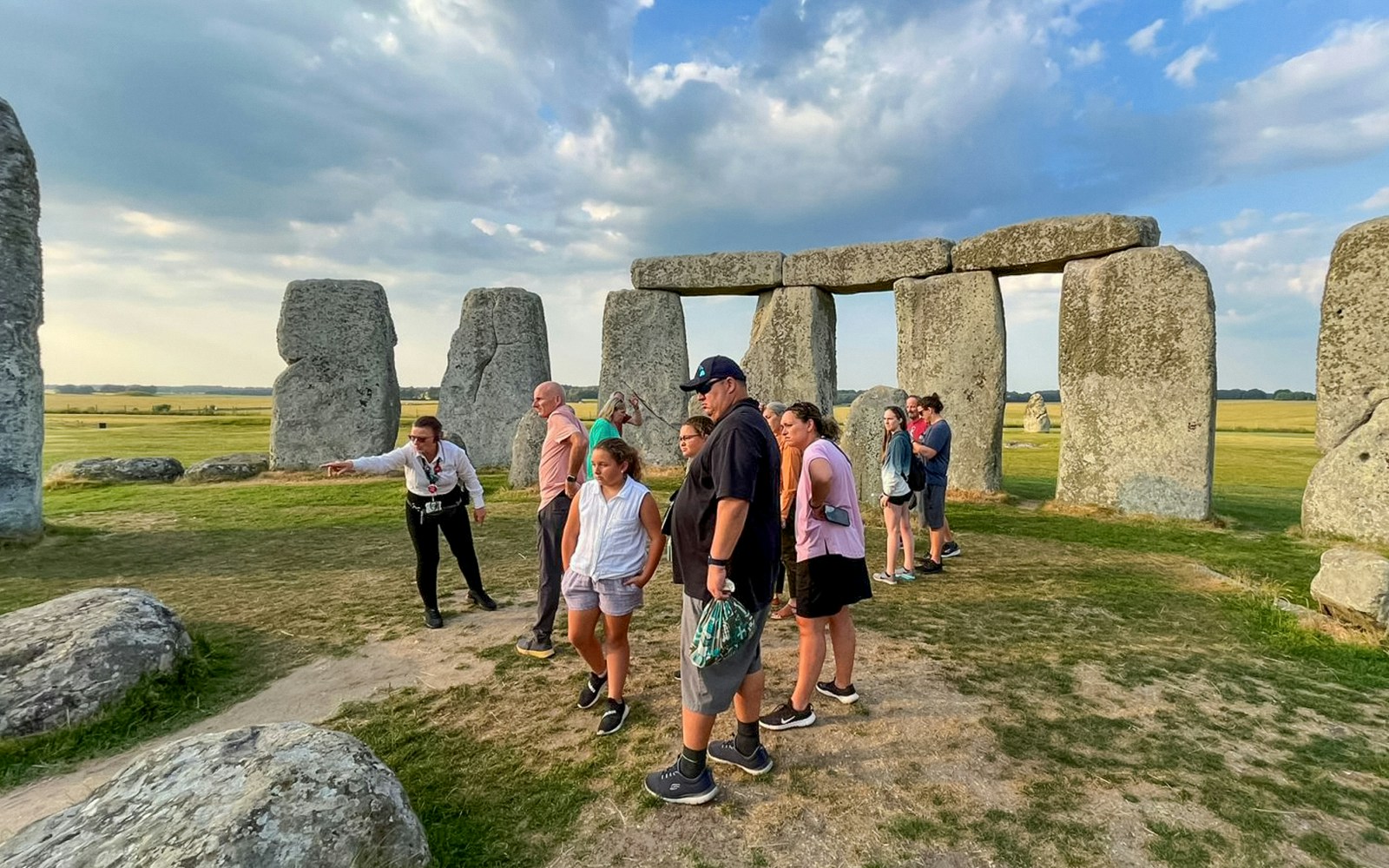 Tourists with guide inside Stonehenge, England, exploring ancient stone circle.