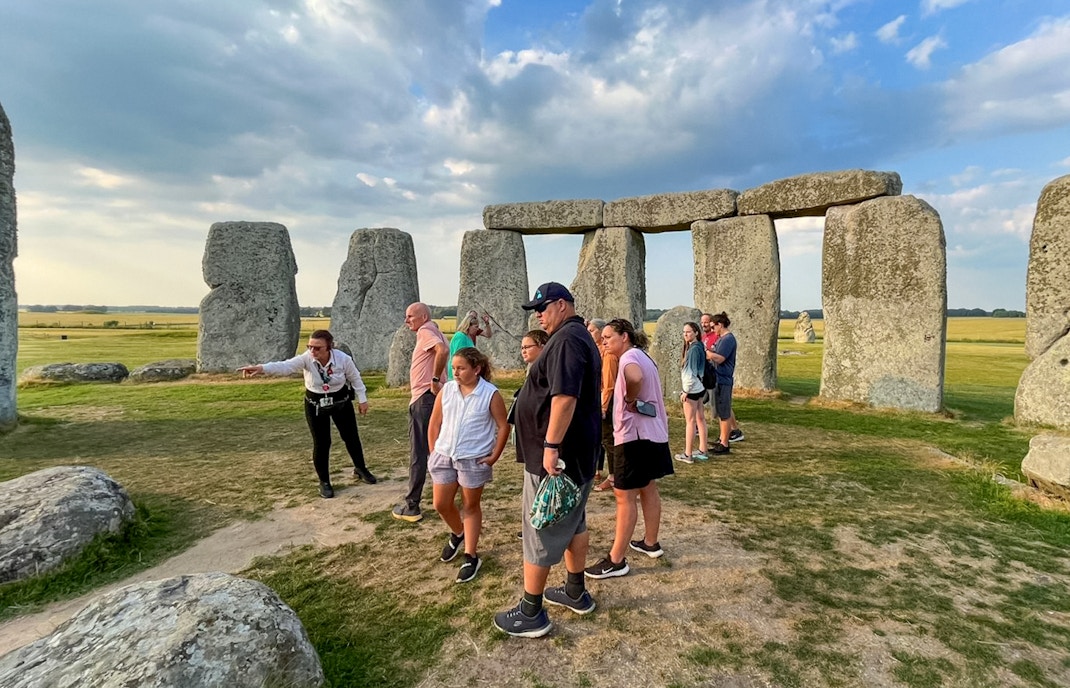 Tourists with guide inside Stonehenge, England, exploring ancient stone circle.