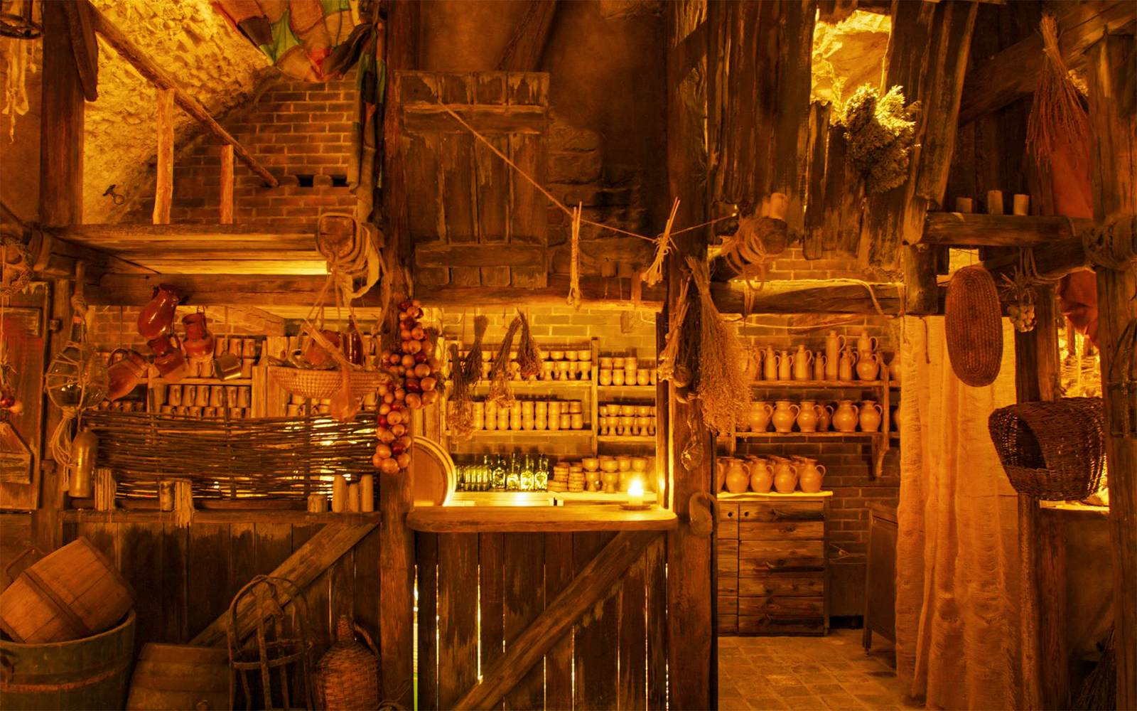 Tavern interior with rustic wooden shelves, clay pots, and hanging herbs for a Medieval Dinner Show.