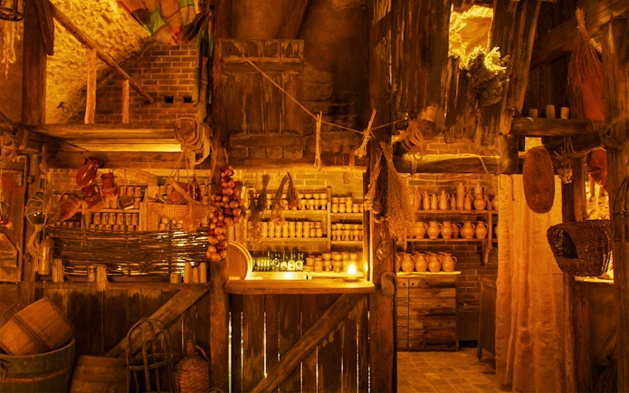 Tavern interior with rustic wooden shelves, clay pots, and hanging herbs for a Medieval Dinner Show.