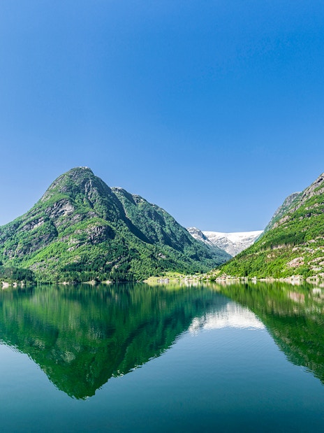 Hardangerfjord view with mountains reflecting in the water, seen from a bus tour in Norway.