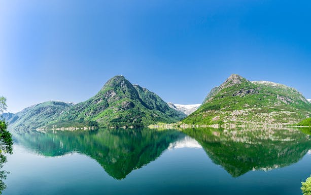 Hardangerfjord view with mountains reflecting in the water, seen from a bus tour in Norway.