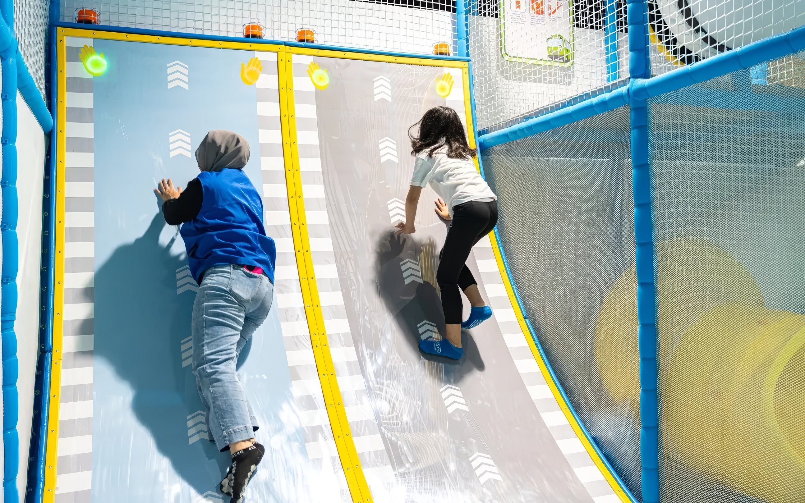 Tourists climbing interactive wall at Tayo Station indoor playground.