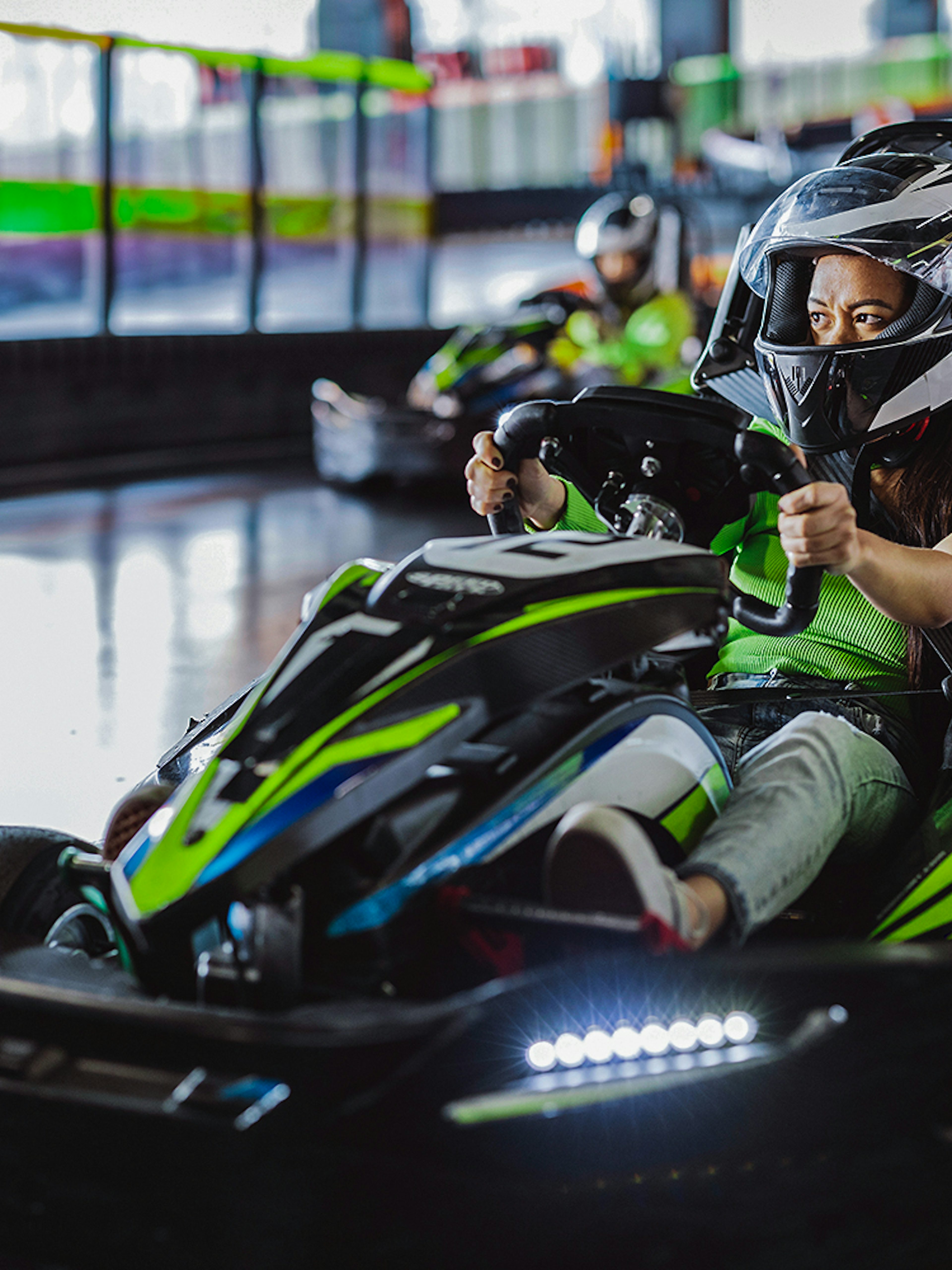 Indoor karting driver wearing helmet on track.