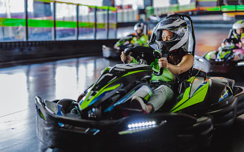 Indoor karting driver wearing helmet on track.