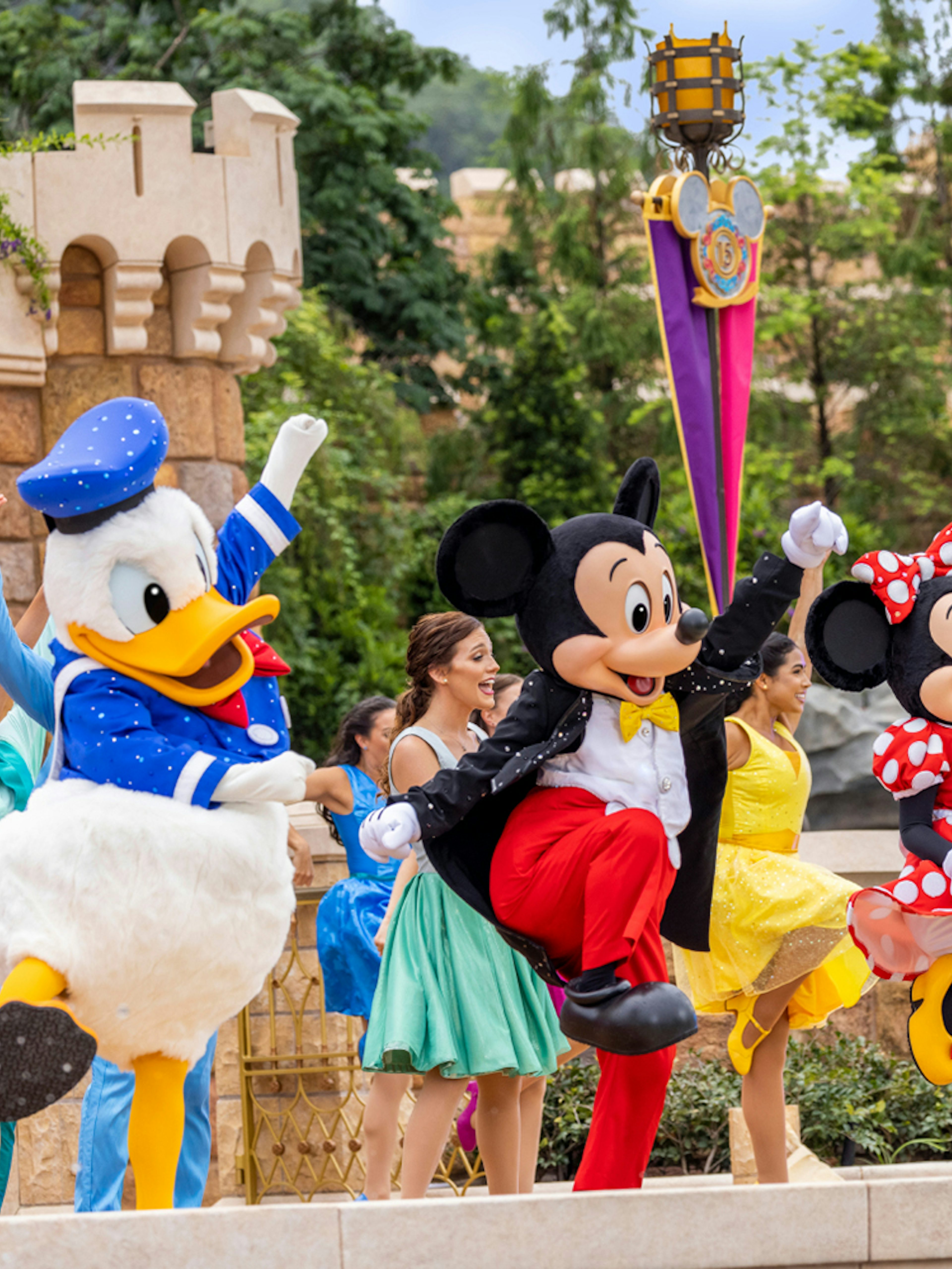 Disney characters performing at Disneyland Hong Kong with castle backdrop.