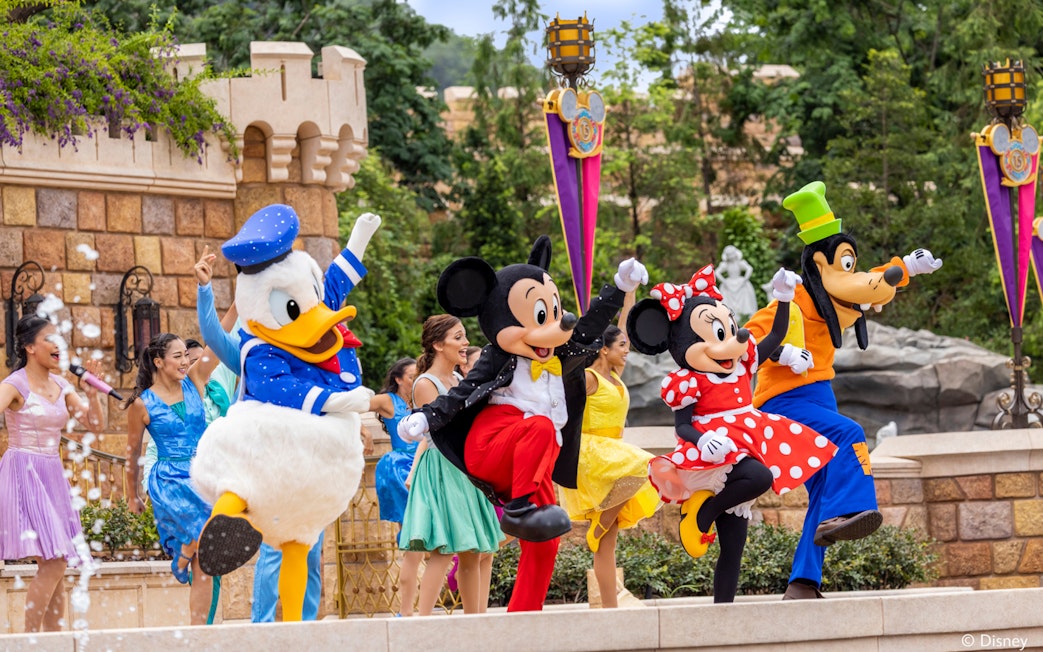 Disney characters performing at Disneyland Hong Kong with castle backdrop.