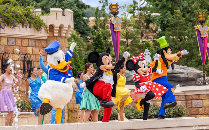 Disney characters performing at Disneyland Hong Kong with castle backdrop.