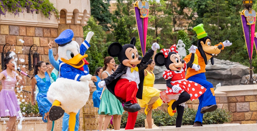 Disney characters performing at Disneyland Hong Kong with castle backdrop.