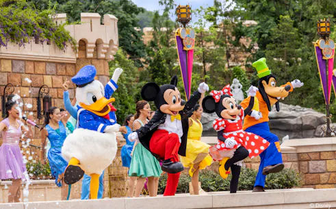 Disney characters performing at Disneyland Hong Kong with castle backdrop.