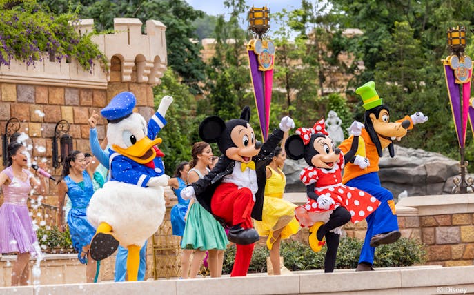 Disney characters performing at Disneyland Hong Kong with castle backdrop.