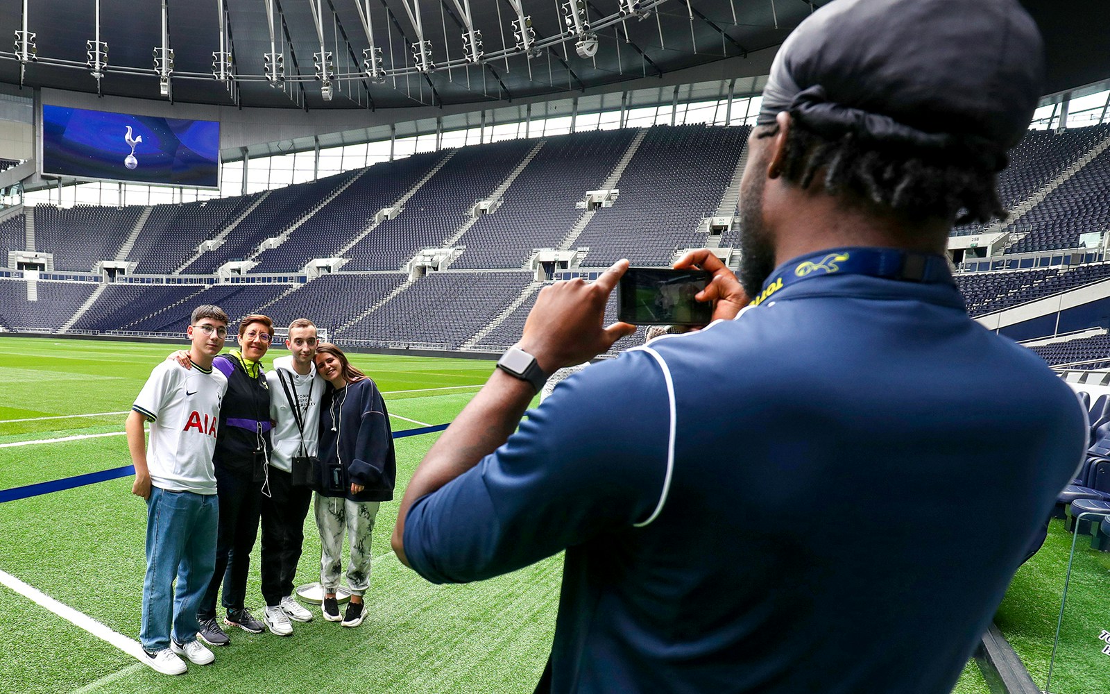 Group posing for a photo on the field at Tottenham Hotspur Stadium, London.