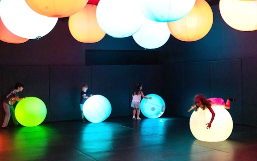 Children playing with glowing spheres at OliOli Children's Museum.