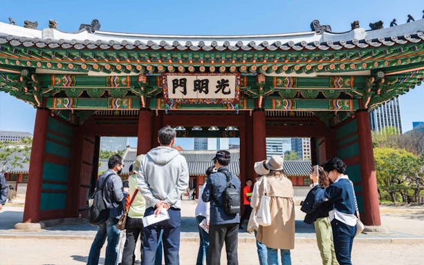 Group of tourists exploring a traditional Korean gate on a guided walking tour.
