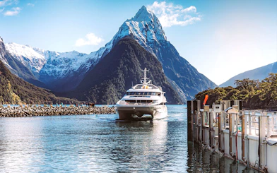 Cruise ship approaching dock with Mitre Peak in Milford Sound, New Zealand.