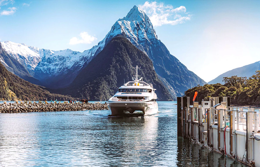 Cruise ship approaching dock with Mitre Peak in Milford Sound, New Zealand.