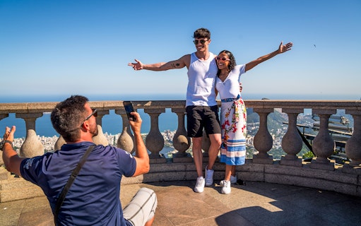 Guide photographing tourists at Christ the Redeemer, Rio de Janeiro.