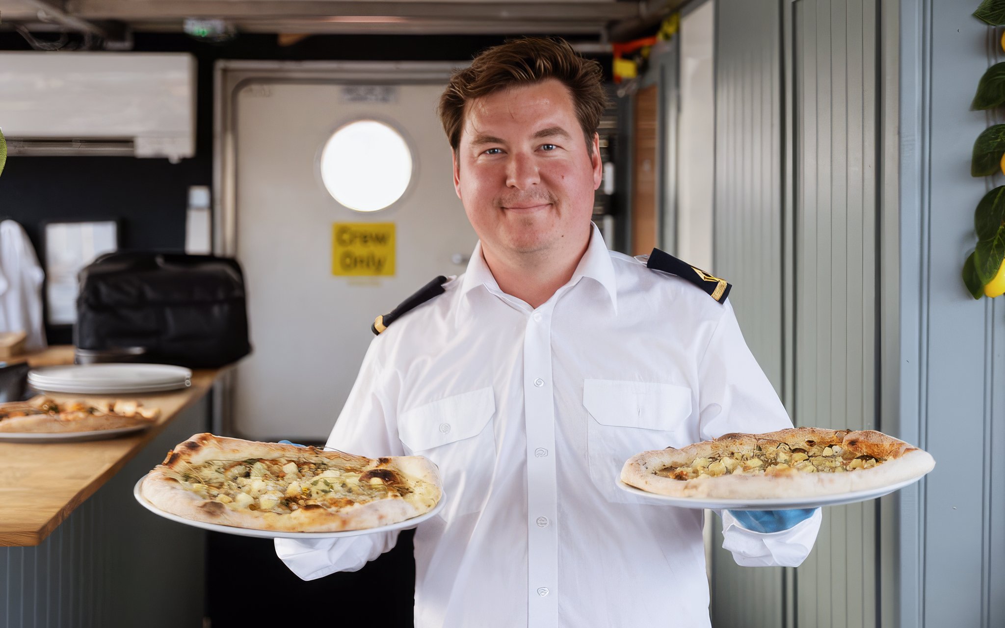 Crew member serving pizza on Stockholm cruise.