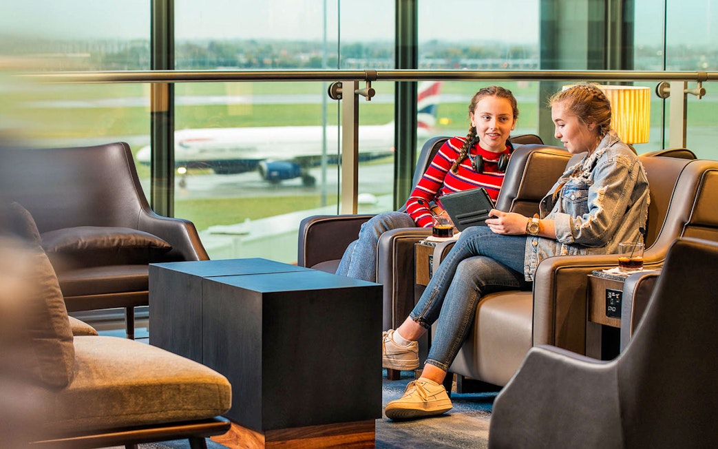 Heathrow Plaza Premium Lounge with travelers relaxing and viewing the runway.