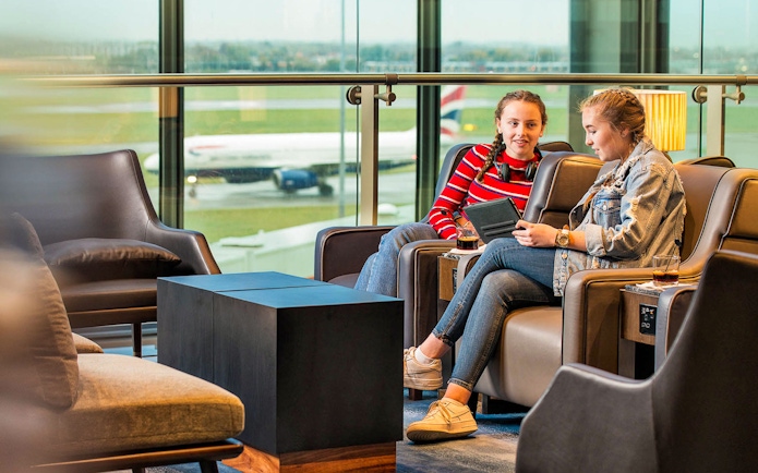 Heathrow Plaza Premium Lounge with travelers relaxing and viewing the runway.
