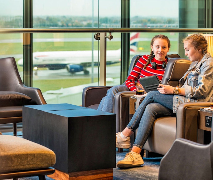 Heathrow Plaza Premium Lounge with travelers relaxing and viewing the runway.