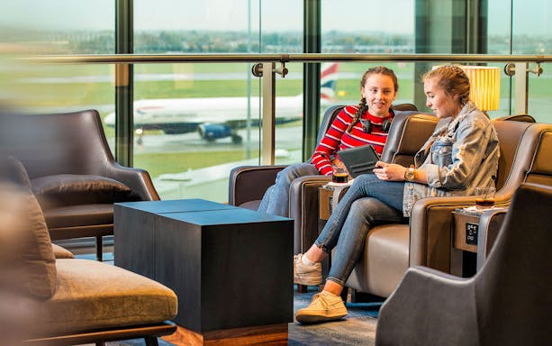 Heathrow Plaza Premium Lounge with travelers relaxing and viewing the runway.