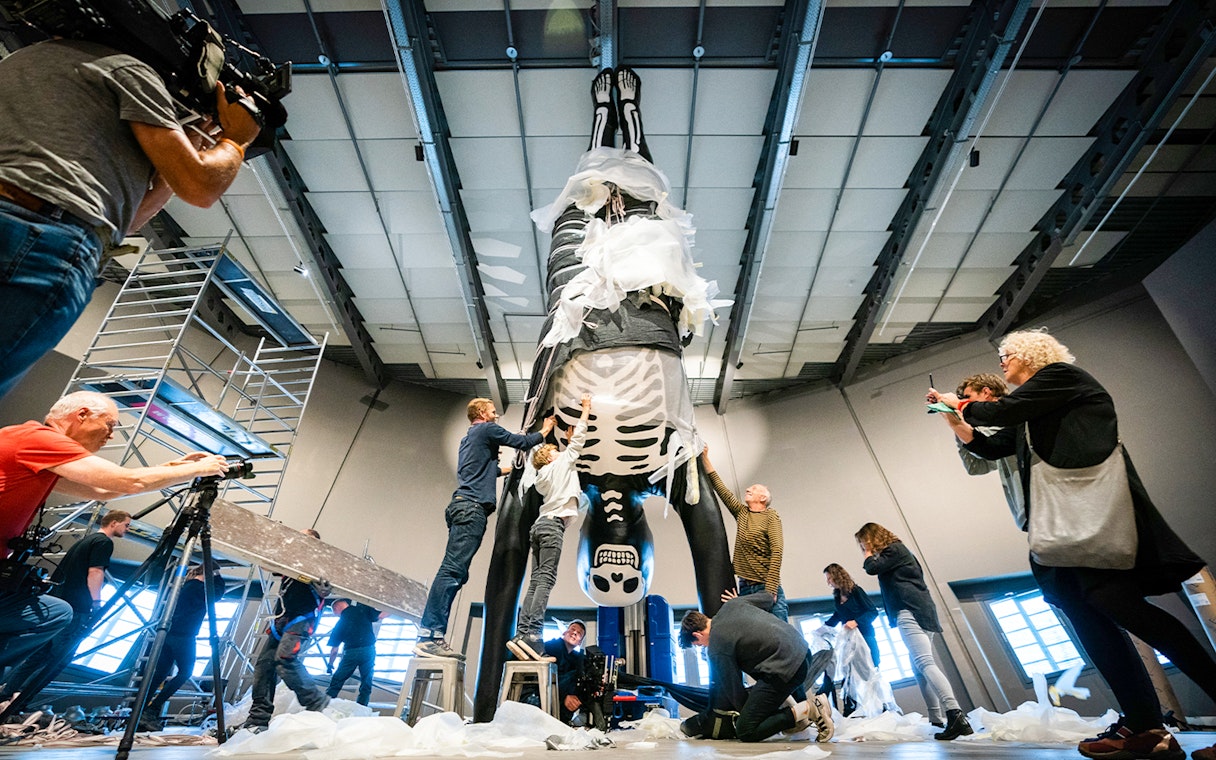People preparing a large skeleton exhibit at NEMO Science Museum.