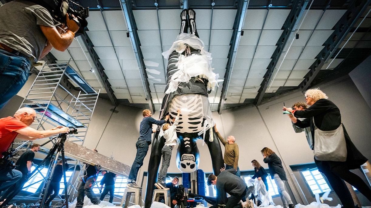 People preparing a large skeleton exhibit at NEMO Science Museum.