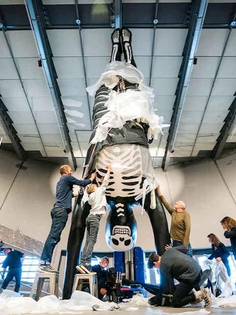 People preparing a large skeleton exhibit at NEMO Science Museum.