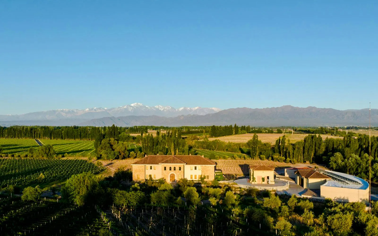 Bodega Krontiras winery in Mendoza, Argentina, surrounded by vineyards with Andes mountains in the background.
