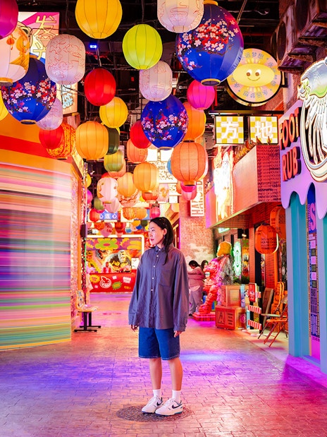 Tourist exploring vibrant lantern-lit street in House of Hype, Dubai.
