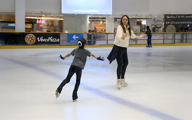 Coach guiding girl on ice at Blue Ice Snow Park, Johor Bahru.