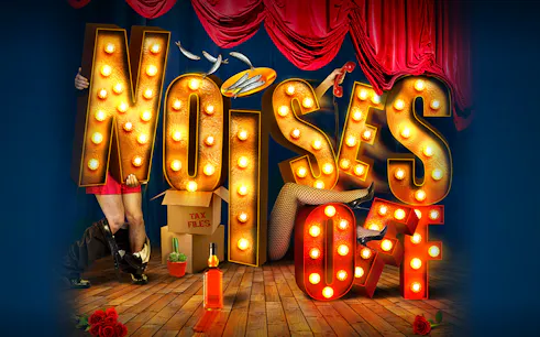 Theater stage with "Noises Off" in illuminated letters, props, and red curtains.