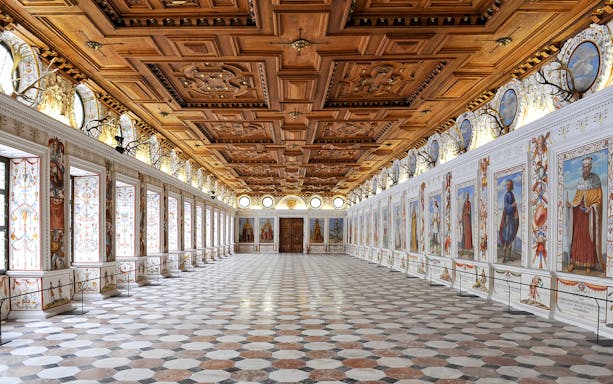 Ambras Castle Innsbruck's Spanish Hall with ornate wooden ceiling and historical portraits.