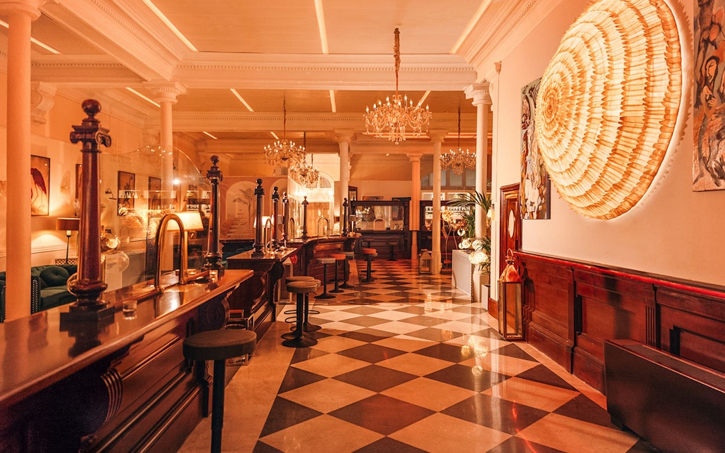 Elegant interior of a bar with chandeliers and checkered floor in Laietana, Barcelona.