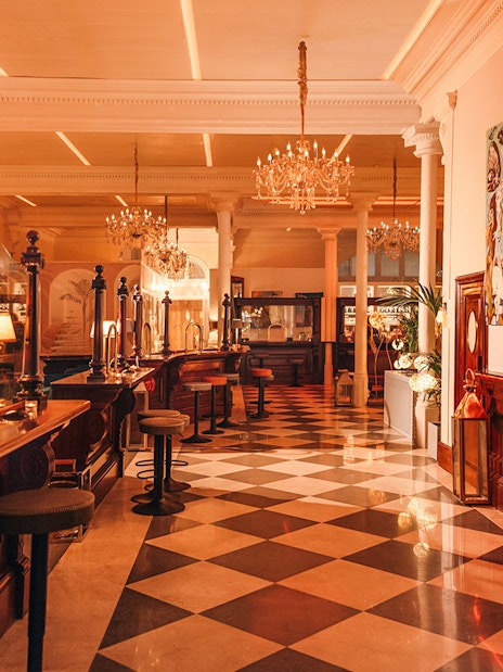 Elegant interior of a bar with chandeliers and checkered floor in Laietana, Barcelona.