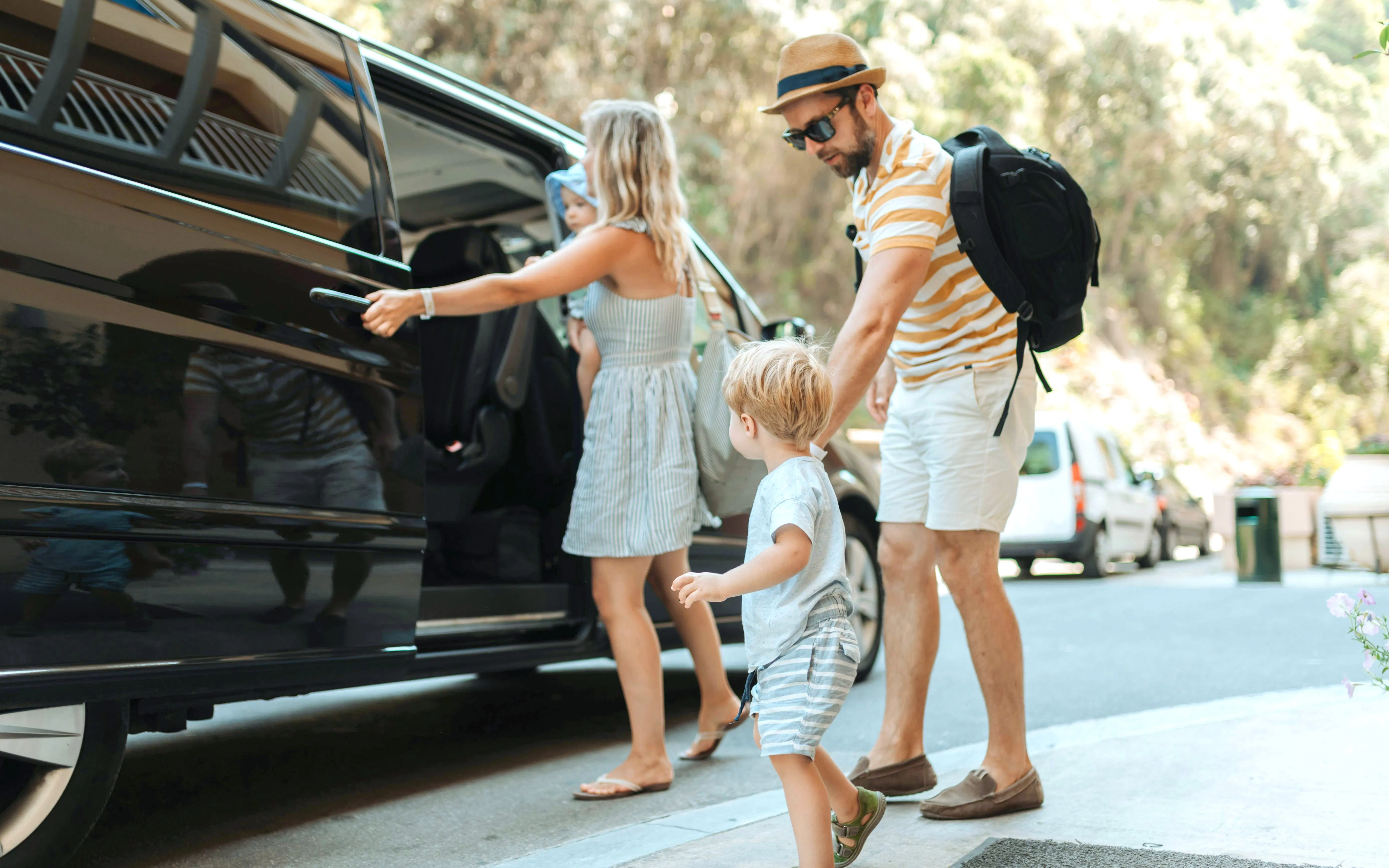 Parents with toddlers boarding a car for hotel pickup.