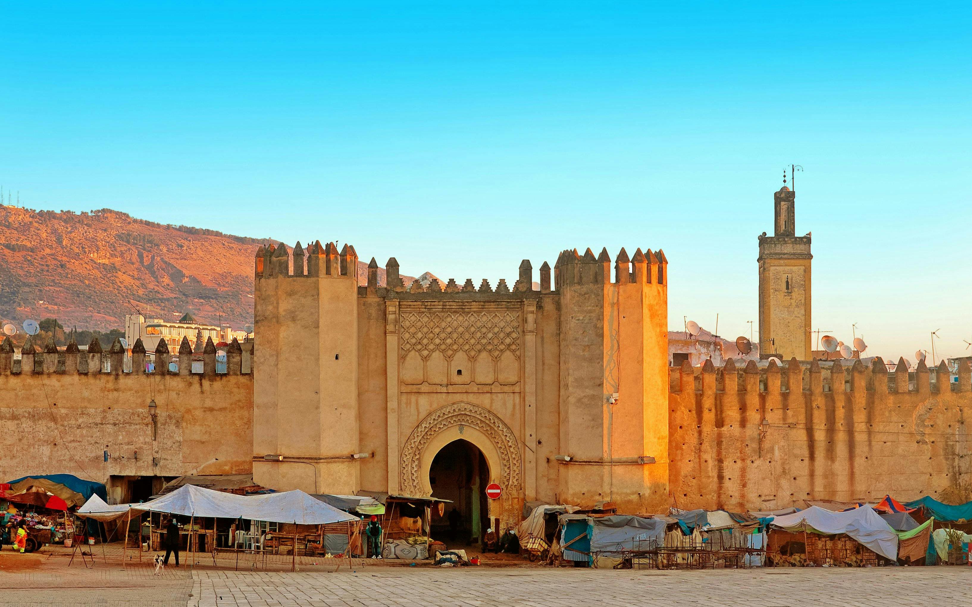 Gate to ancient medina of Fez, Morocco with market stalls in front.