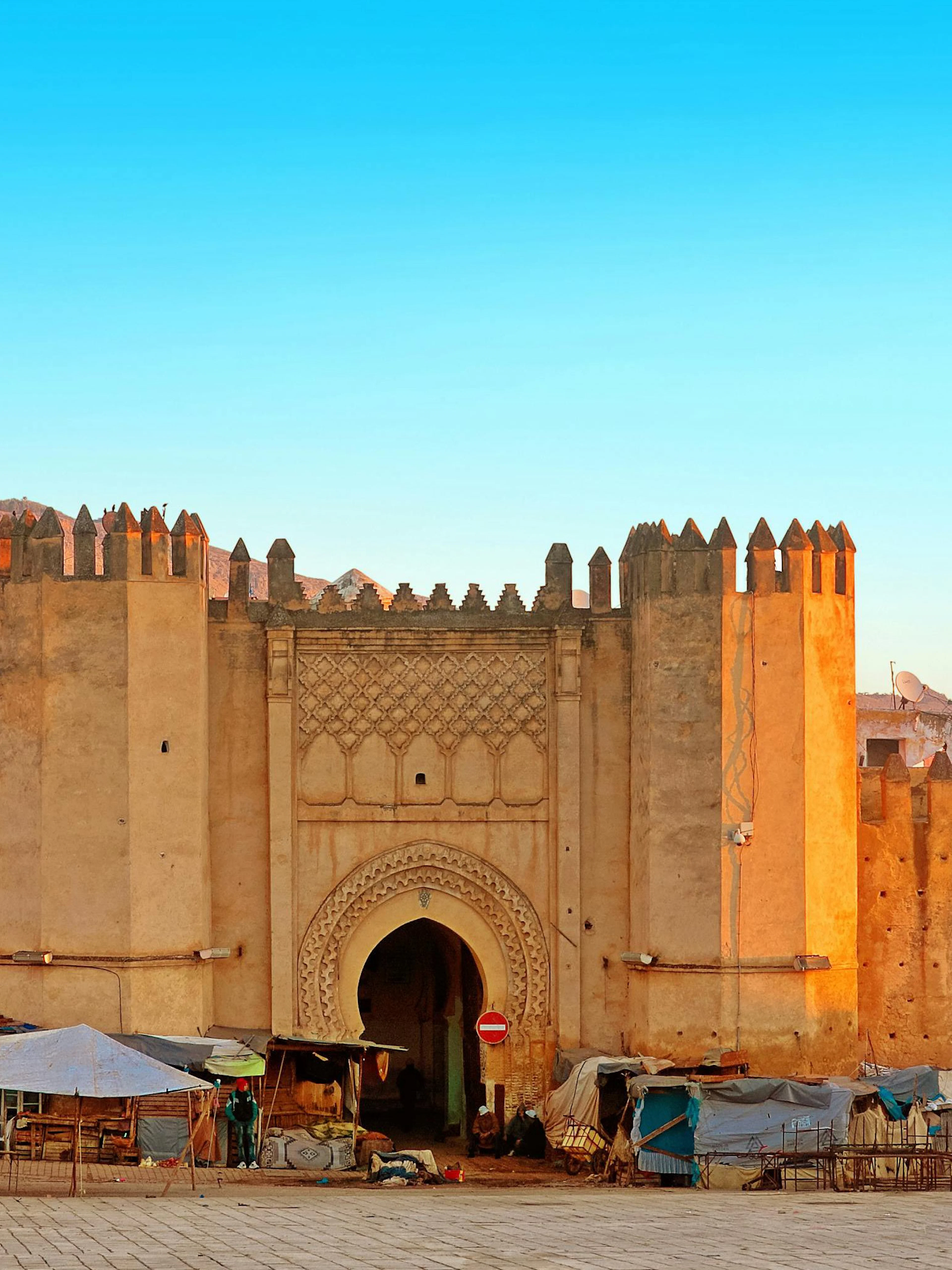 Gate to ancient medina of Fez, Morocco with market stalls in front.