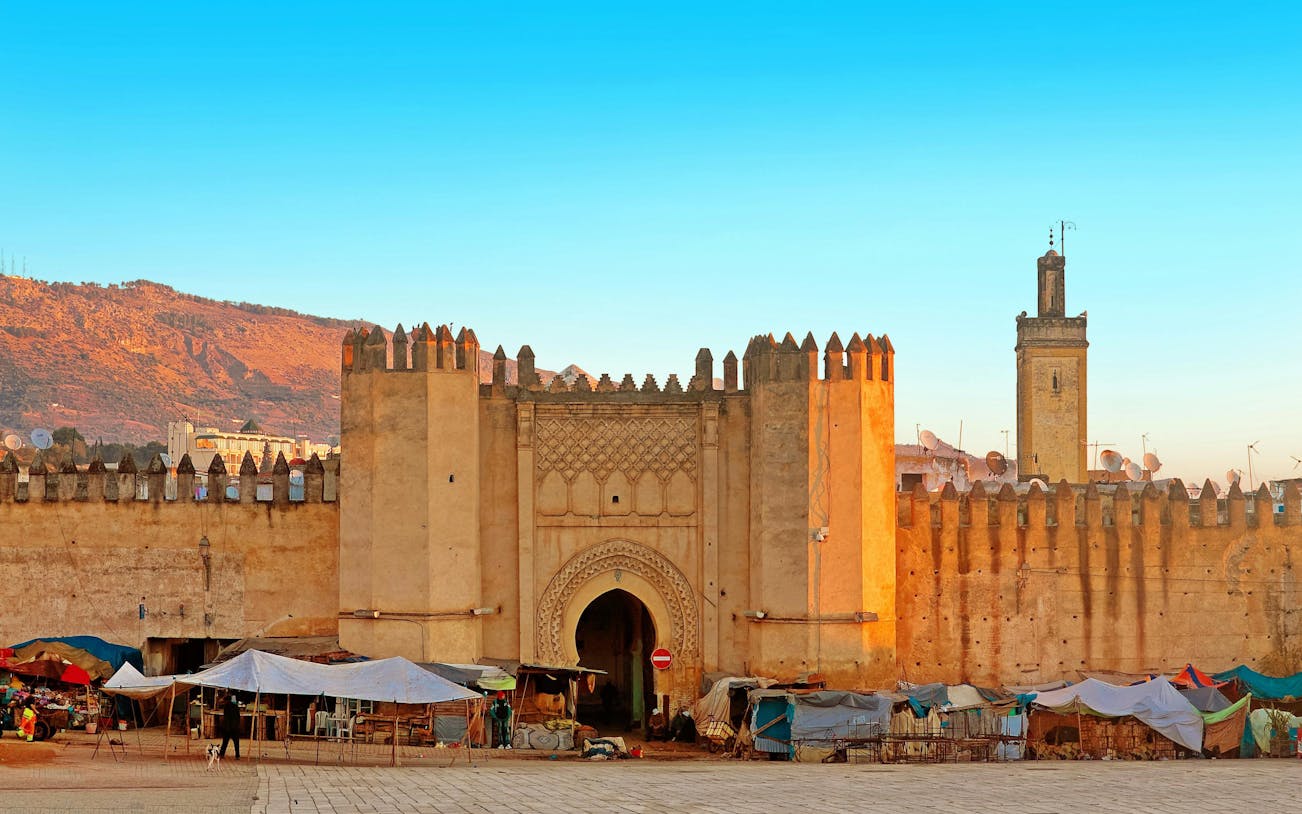 Gate to ancient medina of Fez, Morocco with market stalls in front.