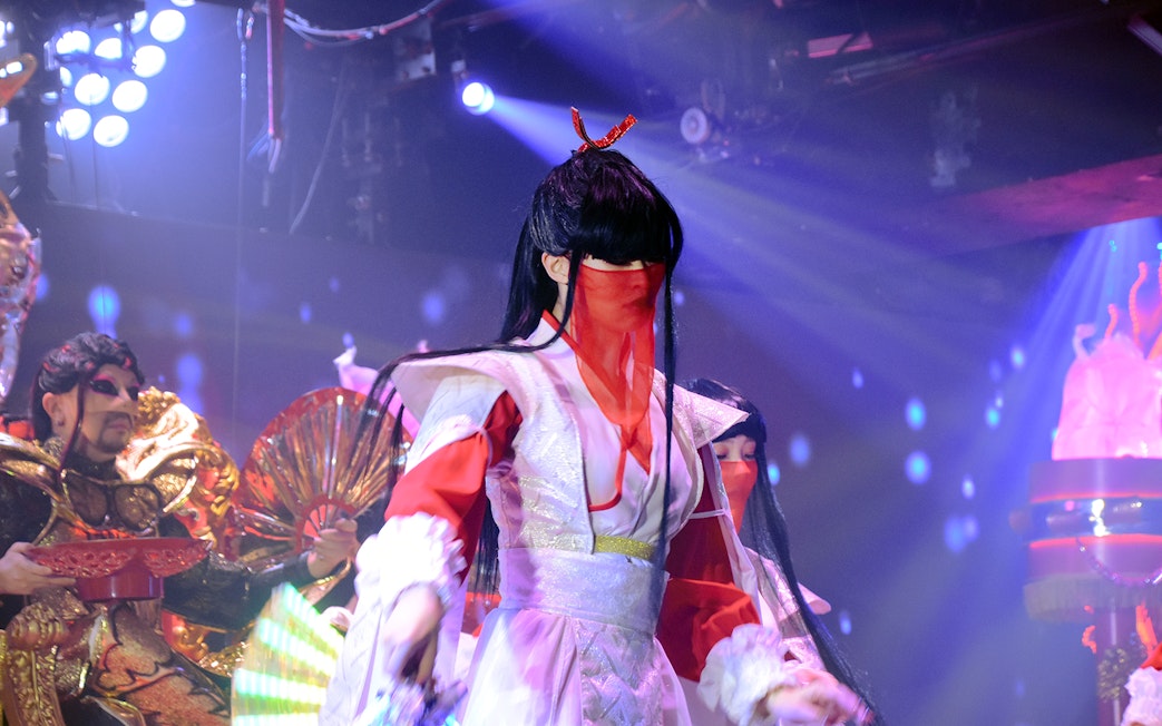 Samurai-themed performers on stage at a restaurant show with vibrant costumes and lighting.