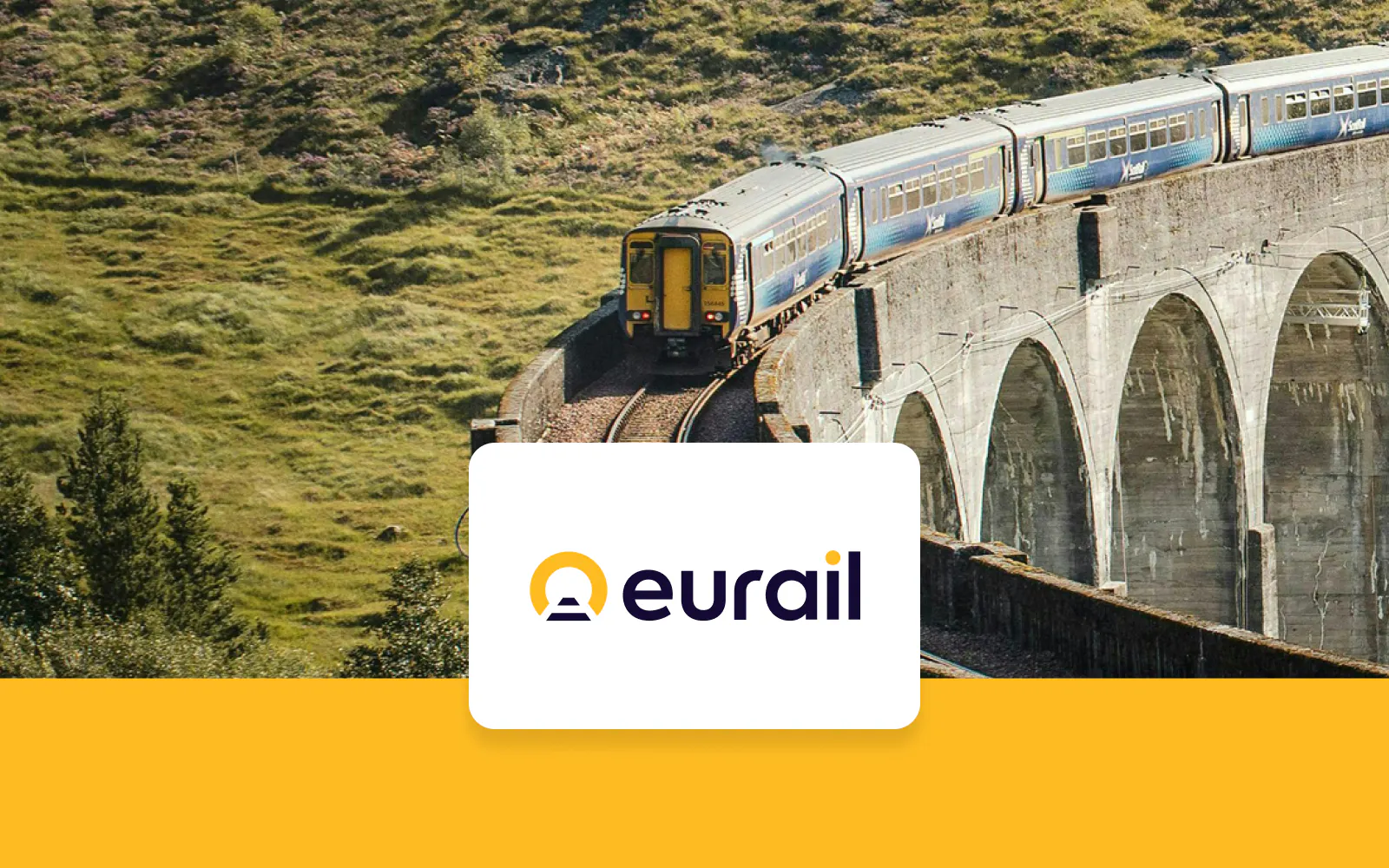 Train crossing a stone viaduct in a scenic European landscape.