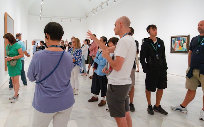 Visitors on a guided tour at Prado & Reina Sofia Museum, viewing artwork with a guide.