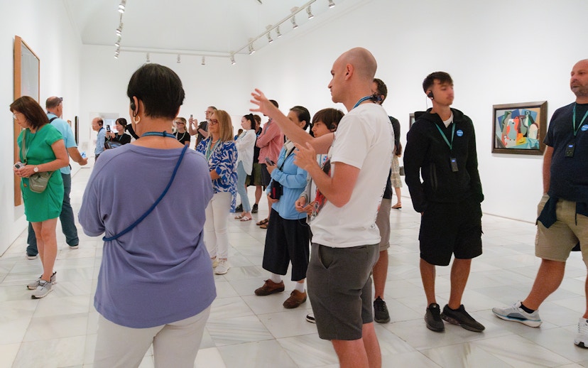 Visitors on a guided tour at Prado & Reina Sofia Museum, viewing artwork with a guide.