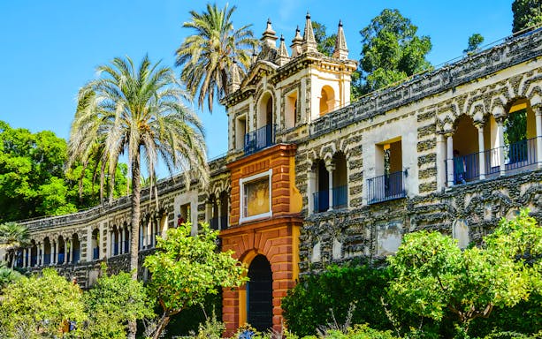 Courtyard of Alcazar Seville with ornate architecture and lush greenery.
