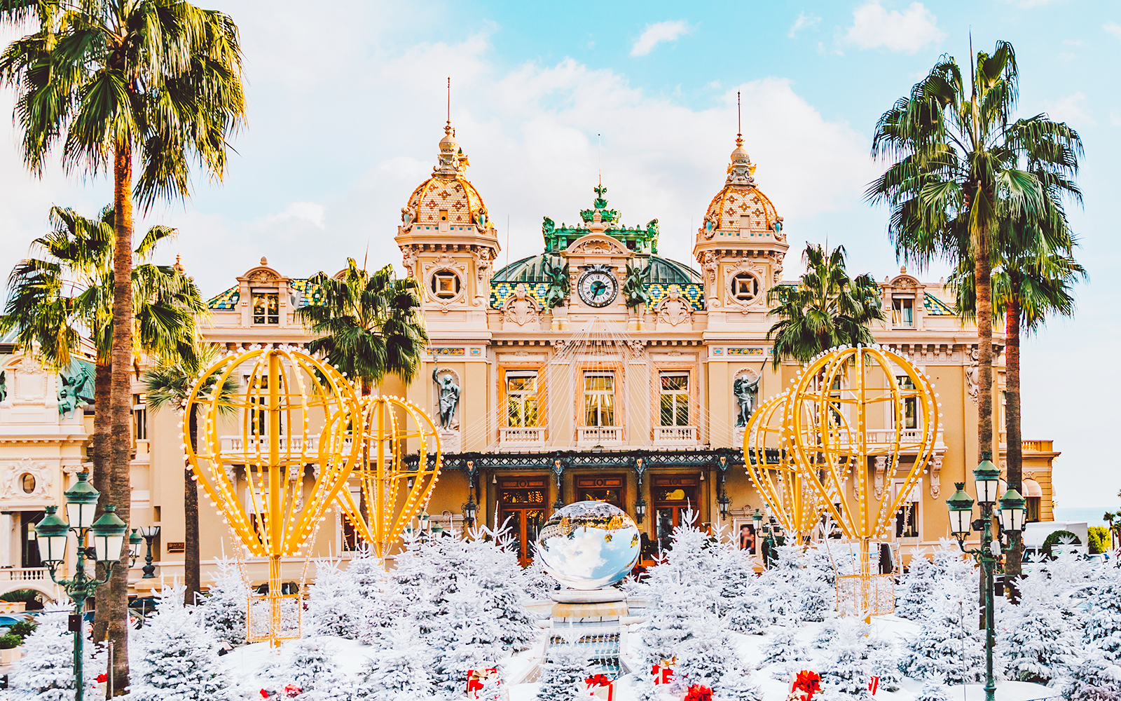 Festive decorations and snow-covered trees in front of a grand building in Nice for New Year celebrations.
