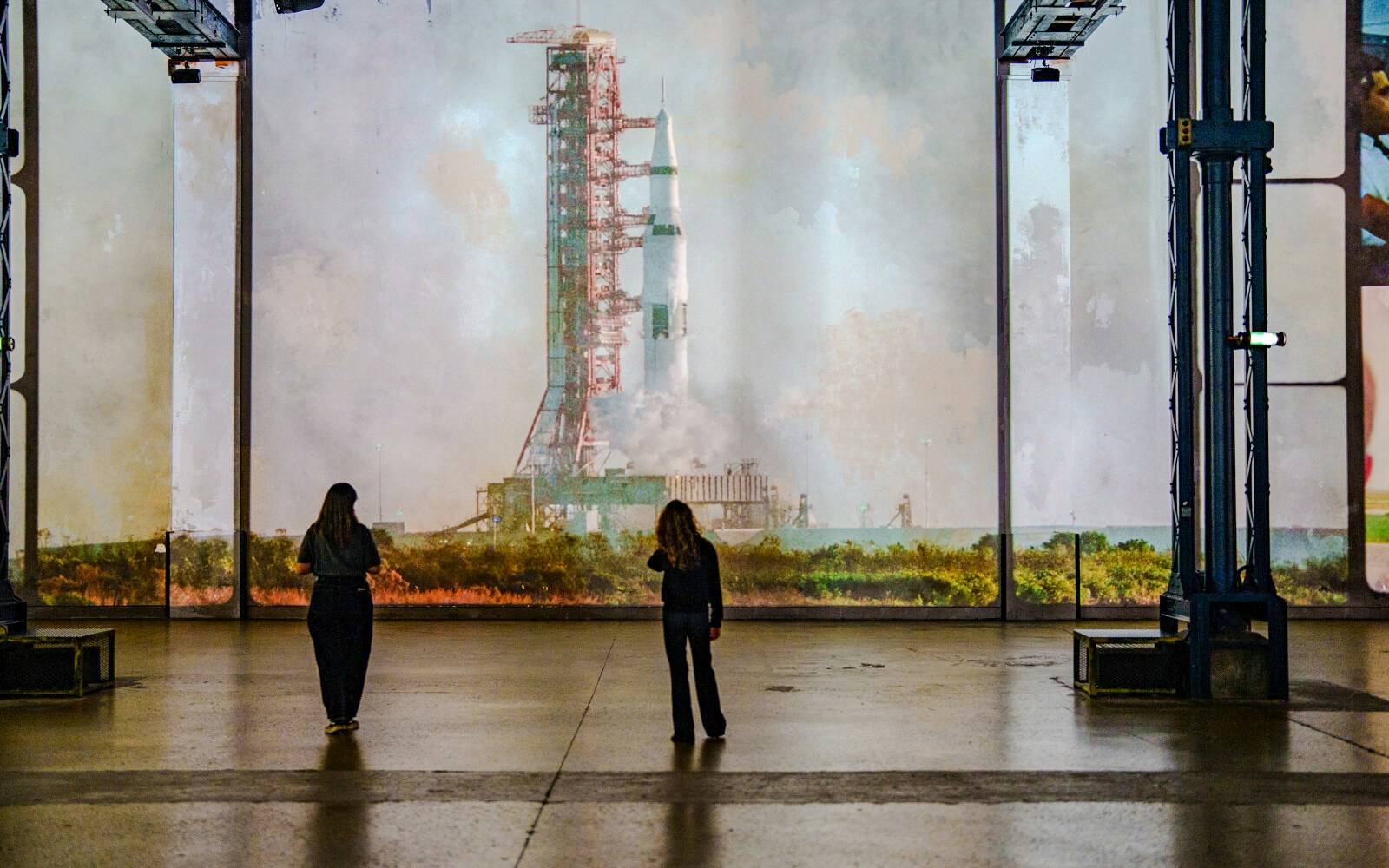 Visitors viewing rocket projection at The Moonwalkers Exhibition, Atelier des Lumières.