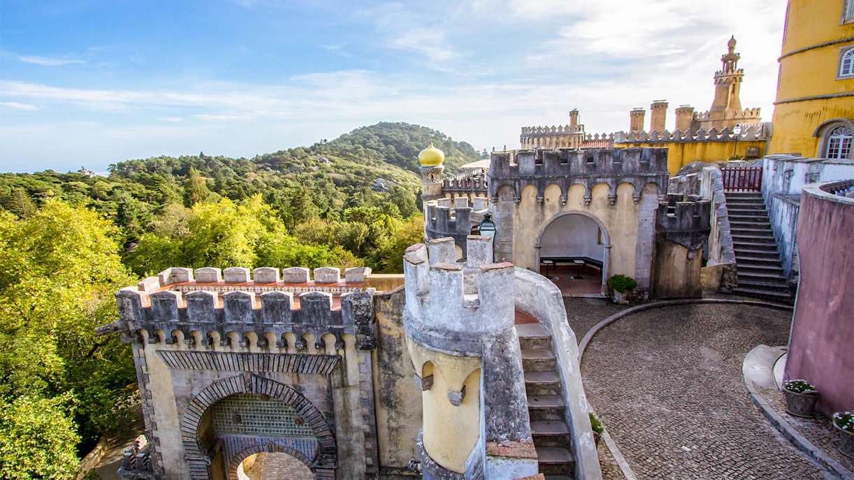 Pena Palace's colorful architecture with arched entrance and scenic forest view in Sintra, Portugal.